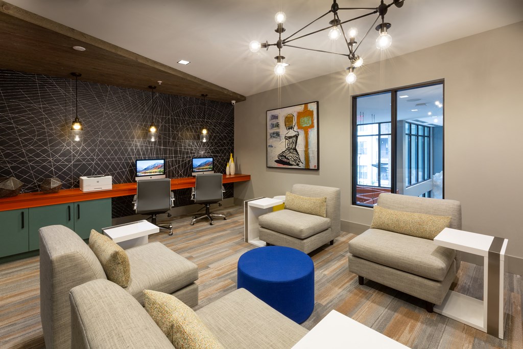 a lounge area with couches and chairs and a desk with a computer