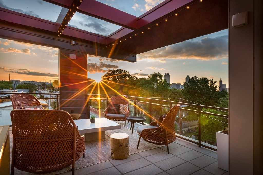 a balcony with a view of a sunset and chairs and a table