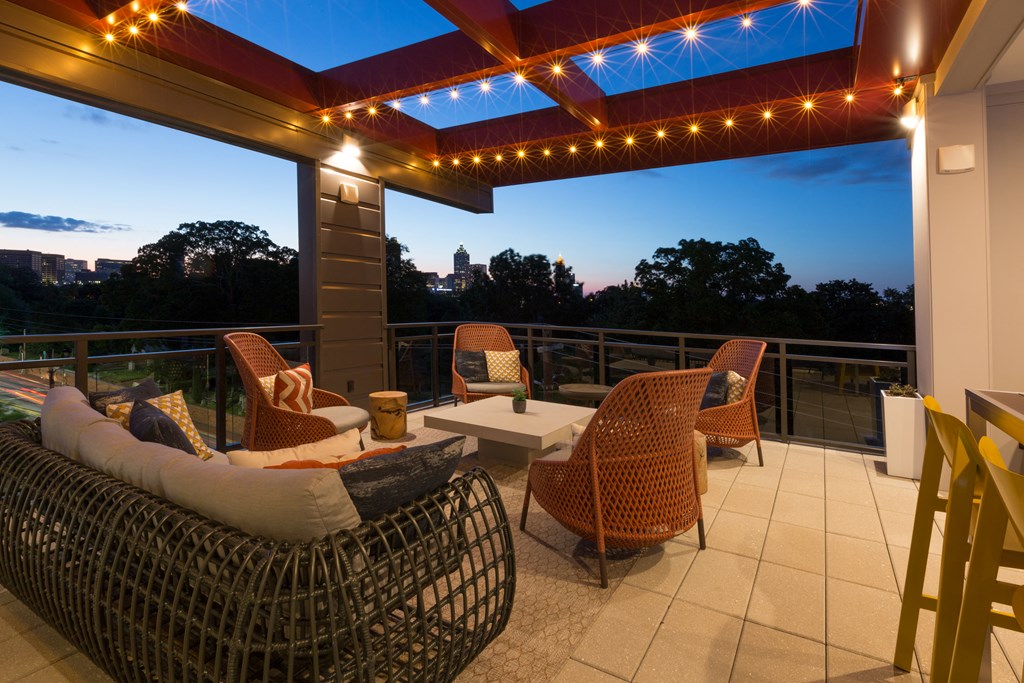 a covered patio with wicker chairs and a table and lights