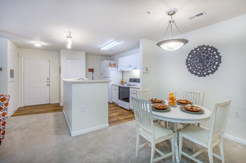 a dining room and kitchen with a white table and chairs
