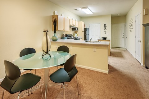 a dining room with a glass table and chairs in front of a kitchen