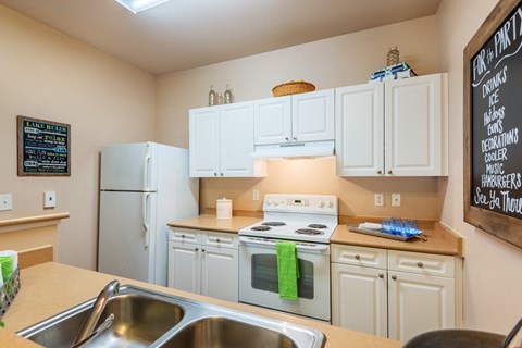 a kitchen with white cabinets and appliances and a sink