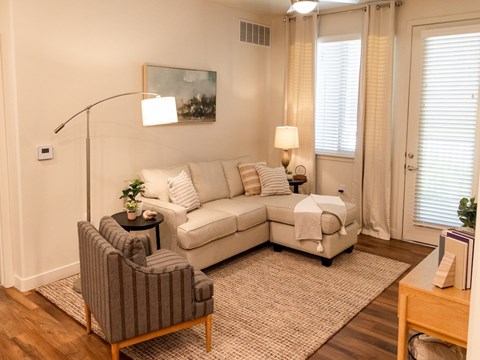A living room with a grey striped armchair, a white sofa, and a small table with a plant on it.