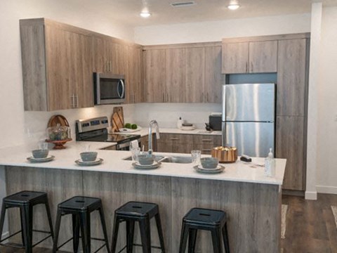 a kitchen with a counter with three bar stools