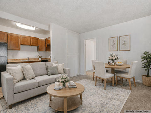 A living room with a couch, chairs, and a dining table set up.