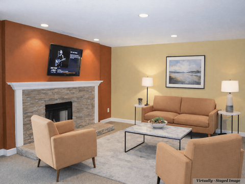 A living room with a fireplace, two chairs, a couch, and a painting on the wall.