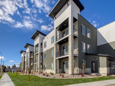 A modern apartment building with a well-maintained lawn in front.