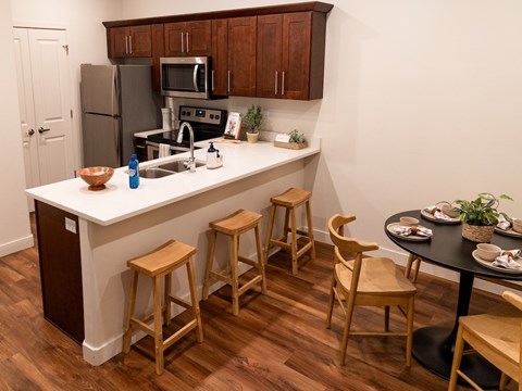 A kitchen with a white counter top and wooden floors.