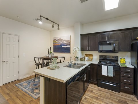 A kitchen with a white counter top and black cabinets.