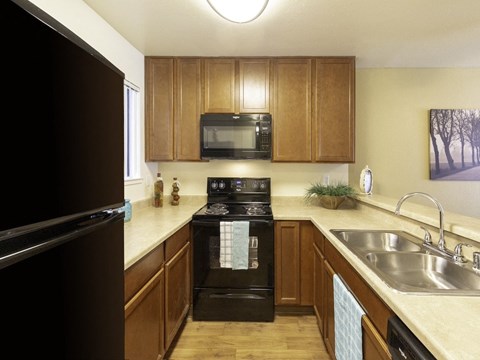 a kitchen with wood cabinets and black appliances and a sink