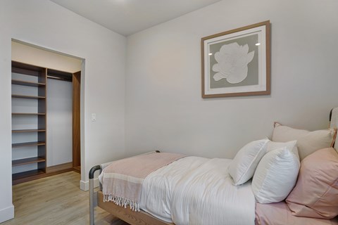 A bedroom with a bed, pillows, and a picture on the wall.