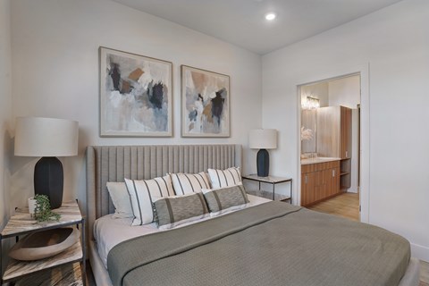 A bedroom with a large bed and two abstract paintings on the wall.
