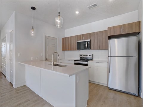 A modern kitchen with a stainless steel refrigerator and white cabinets.