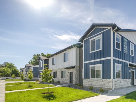 a row of blue and white houses with green grass and a sidewalk
