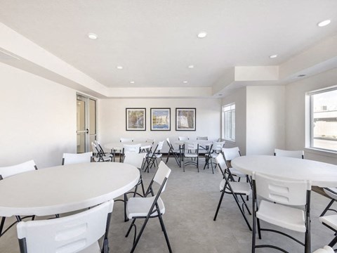 A white dining room with multiple tables and chairs.