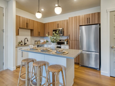 A kitchen with wooden cabinets and a stainless steel refrigerator.