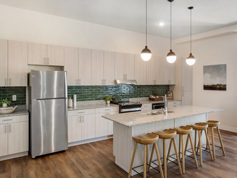 A kitchen with a stainless steel refrigerator and wooden bar stools.