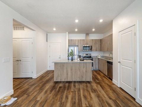 an open kitchen with a large island and wooden floors