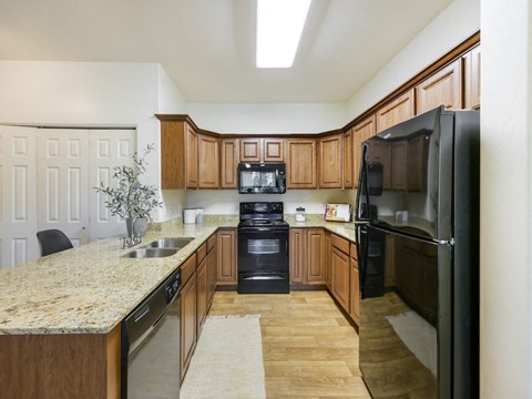 a kitchen with black appliances and a marble counter top