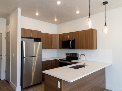 A kitchen with a stainless steel refrigerator and wooden cabinets.