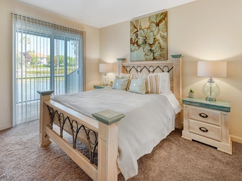 A bedroom with a large bed, two nightstands, and a painting on the wall.