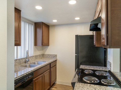 a kitchen with granite counter tops and a black refrigerator