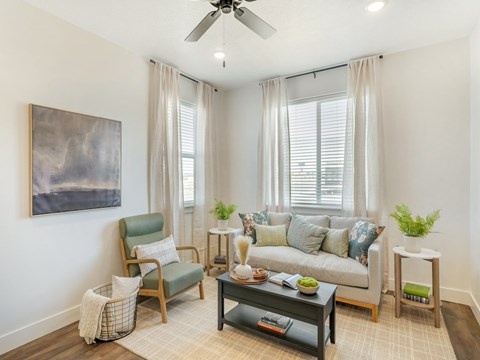A living room with a chair, a couch, a coffee table, and a painting on the wall.