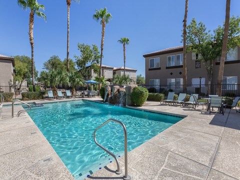 A swimming pool surrounded by palm trees and lounge chairs.
