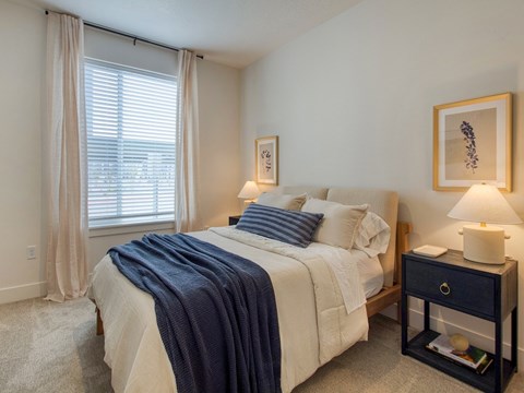 A bedroom with a bed, nightstand, and window.