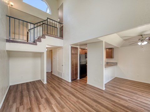 A spacious room with wooden flooring and a balcony with a railing.