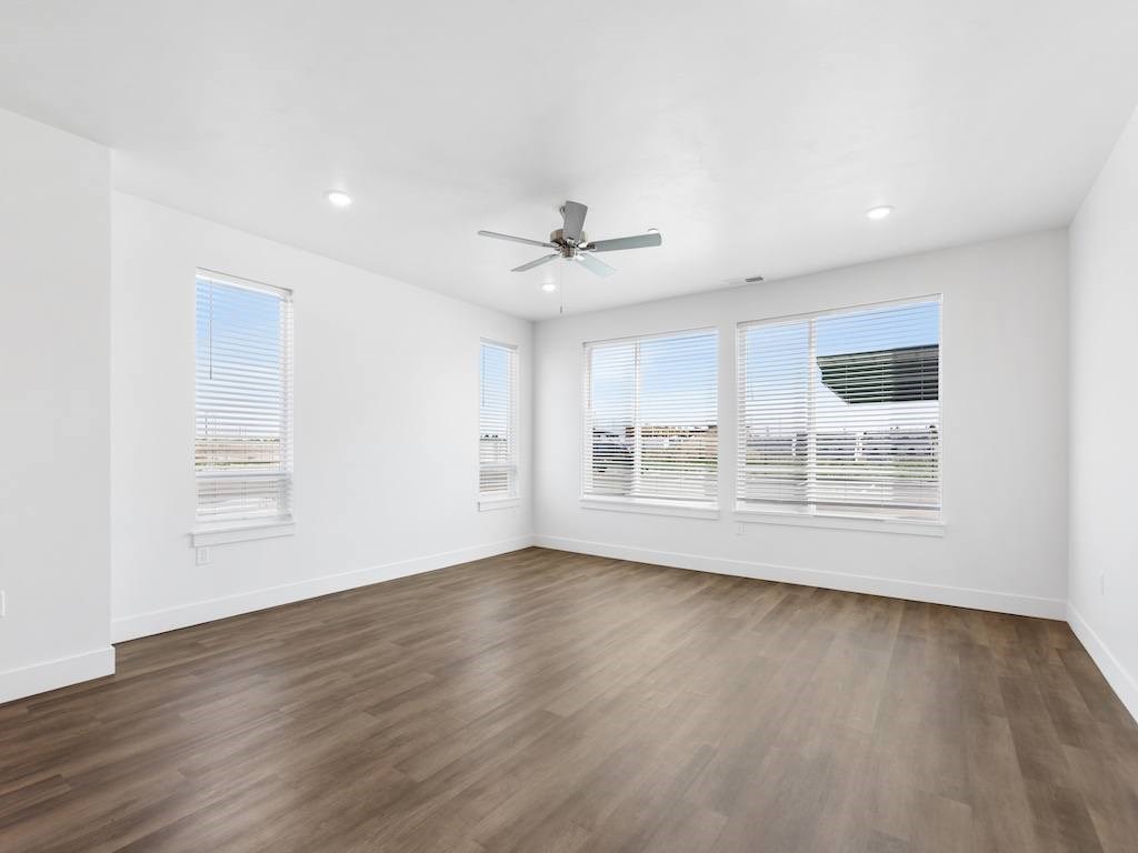 A room with a ceiling fan and wooden flooring.