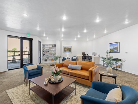 A living room with a brown sofa, blue armchair, and a coffee table with a vase of flowers on it.