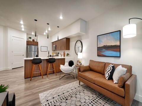 A living room with a brown couch and a painting on the wall.