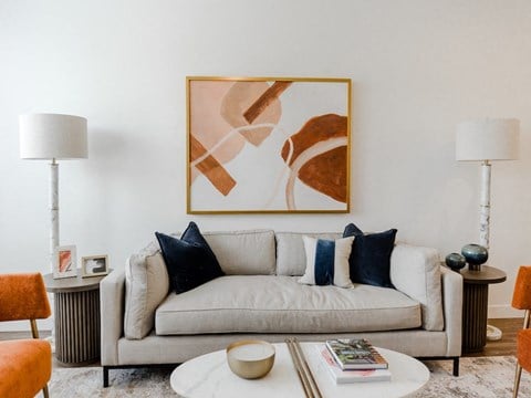 a living room with a white couch and a painting on the wall