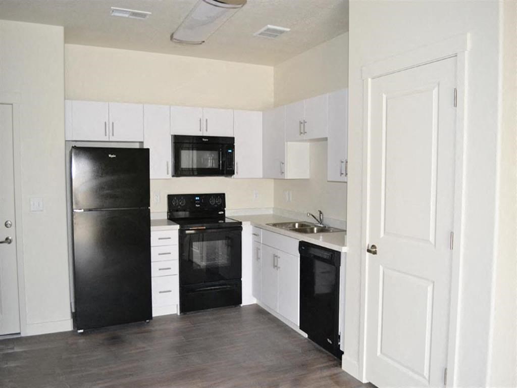 Modern Kitchen with Black Appliances and White Cabinets at Kimpton Square Senior Apartments