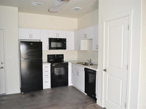 Modern Kitchen with Black Appliances and White Cabinets at Kimpton Square Senior Apartments