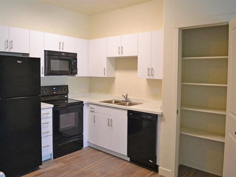 Modern Kitchen with Black Appliances and White Cabinets at Kimpton Square Senior Apartments