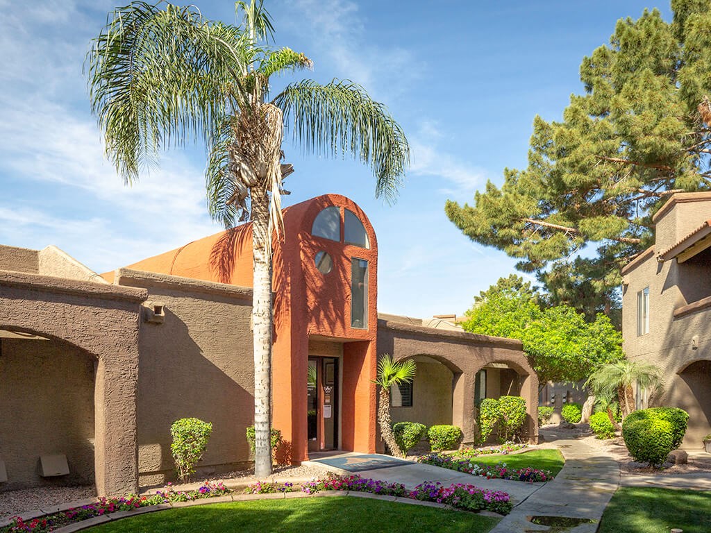 Building exterior with palm trees and lush grass at Glen Oaks Apartments, Glendale, AZ