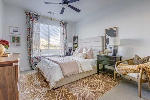 A bedroom with a large bed, a chair, and a ceiling fan.
