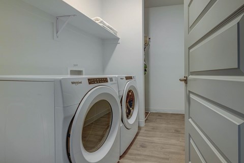 A Whirlpool washing machine is in a small laundry room.
