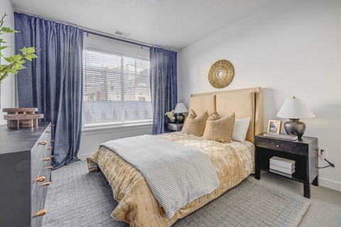 A bedroom with a large bed and a window with curtains.