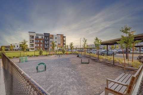 A playground with a basketball court and a fence in front of a building.