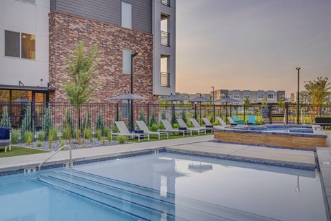 A swimming pool in a residential area with a brick building in the background.
