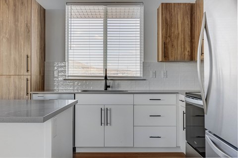A kitchen with white cabinets and a refrigerator.
