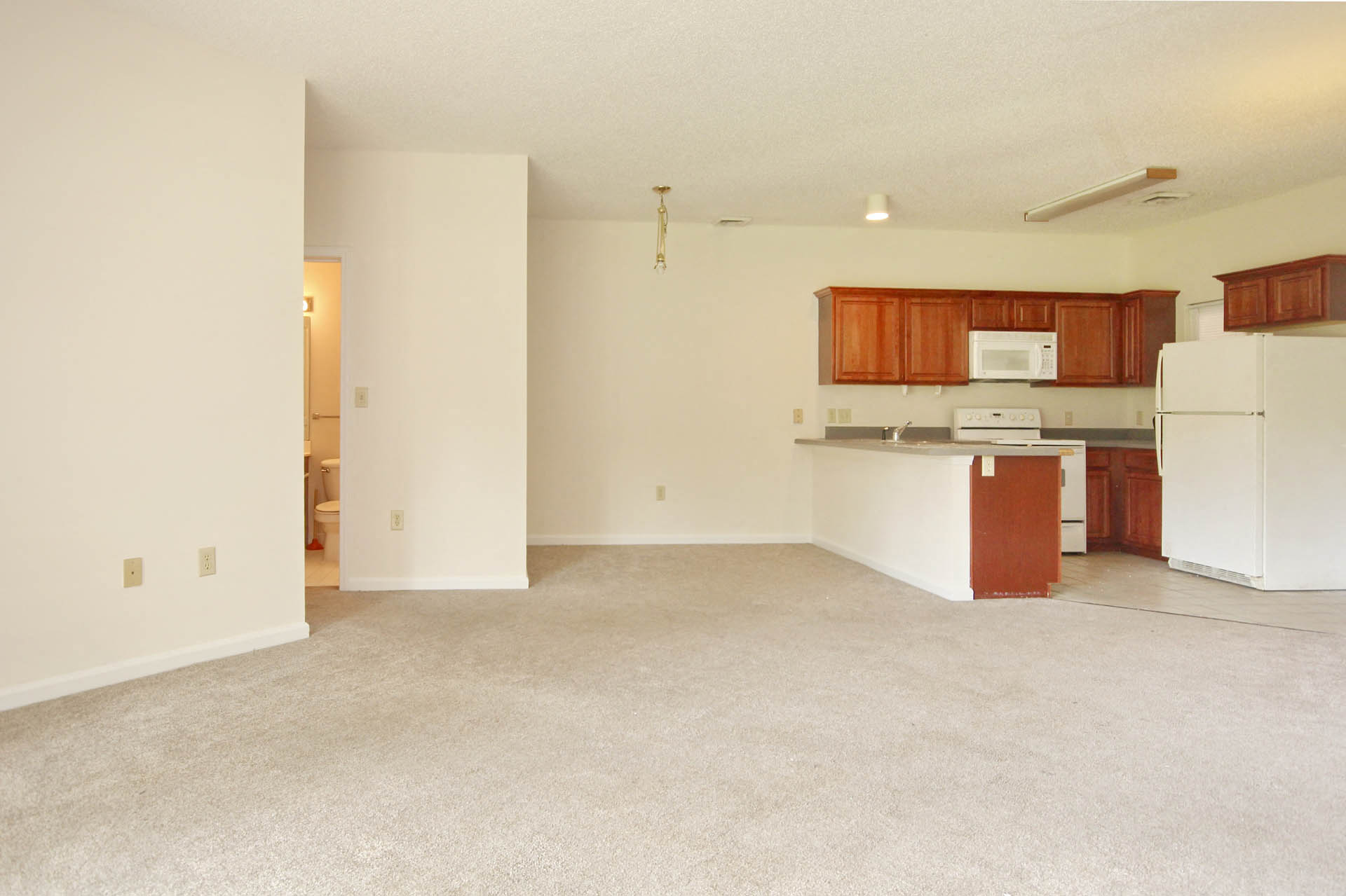 A white room with a kitchenette and a refrigerator.