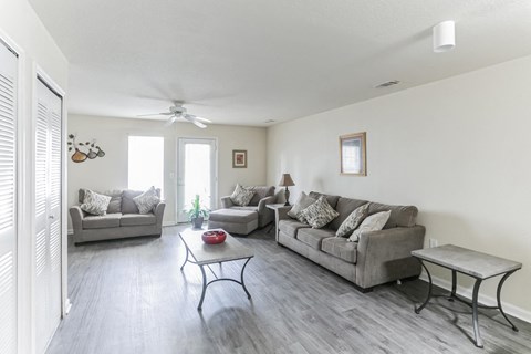 A living room with a grey couch, a coffee table, and a ceiling fan.