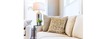 A white couch with a lamp and a plant on a side table.