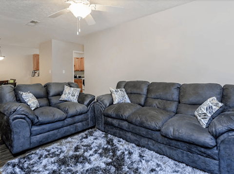 Two grey leather sofas with pillows in a living room.