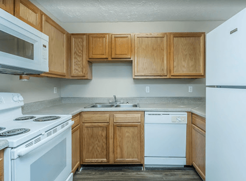 A kitchen with wooden cabinets and a white stove top oven.