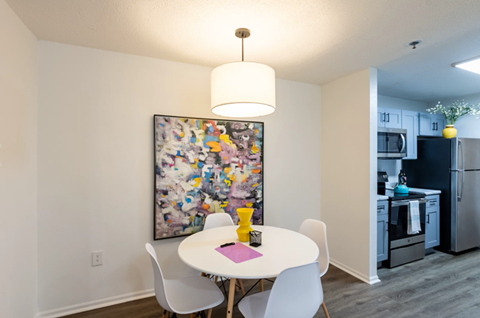 A dining room with a white table and chairs and a painting on the wall.